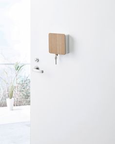 a white wall with a wooden block on it and two hooks attached to the wall