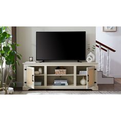 a flat screen tv sitting on top of a wooden entertainment center next to a potted plant