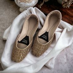 Introducing our Handmade Bridal Khussa with Crystal Embellishments - the epitome of elegance and comfort for your special day. 🌟 Embrace the Charm: Crafted with love and attention to detail, our bridal Khussa shoes are a perfect fusion of tradition and modern aesthetics. The delicate crystal embellishments add a touch of sparkle that will make you shine on your wedding day. 👑 Regal Comfort: We understand that every bride deserves to feel like royalty. That's why our Khussa shoes come with doub Gold Hand Embellished Heels For Reception, Gold Flat Wedding Shoes For Party, Gold Flat Heel Wedding Shoes, Gold Round Toe Flats For Party, Gold Flats With Round Toe For Party, Festive Formal Gold Heels, Gold Almond Toe Flats For Party, Elegant Flats For Reception, Gold Almond Toe Party Flats