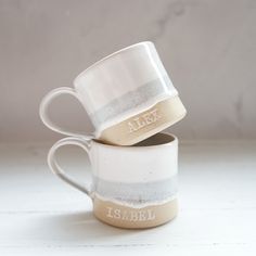 two coffee mugs stacked on top of each other with the word alex printed on them