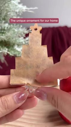 two hands holding a piece of wood with the words, the unique ornament for our home