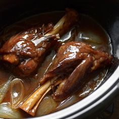 two pieces of meat in a pot with onions and gravy on the side