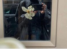 a man taking a selfie in front of a window with a flower on it