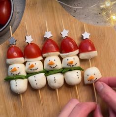 marshmallow snowmen are arranged on skewers with green leaves and red hats