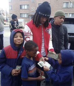 a group of kids standing around each other holding money in their hands and wearing beanies