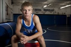 a young man sitting on top of a blue and red basketball court next to a bucket