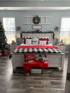 a bedroom decorated for christmas with plaid bedding and red pillows, wreaths on the headboard