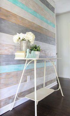 a white table with flowers and books on it in front of a striped wallpaper