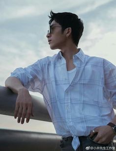 a young man leaning on a rail with his hand on his hip and looking off into the distance