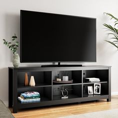 a flat screen tv sitting on top of a black entertainment center next to a potted plant