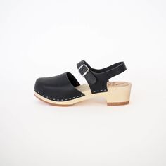 Discover The Charlie Clog, our contemporary twist inspired by the classic Mary Jane. This timeless closed-toe, design features an adjustable back strap and boasts the broadest toe among our closed-toe styles. Whether worn barefoot or paired with socks or tights of any thickness, The Charlie is versatile. The low heel option caters to those with flatter feet or a preference for comfort in daily wear, while the high base style introduces a modern and slightly more dressy option. Both base choices Modern Closed Toe Clogs With Buckle Closure, Modern Sandals With Wooden Heel And Closed Toe, Modern Clogs With Rubber Sole And Open Heel, Modern Open Heel Clogs With Rubber Sole, Black Closed Toe Clogs With Heel Strap, Black Clogs With Ankle Strap And Leather Sole, Black Ankle Strap Clogs With Leather Sole, Modern Closed Toe Clogs With Stacked Heel, Black Slingback Clogs With Heel Strap