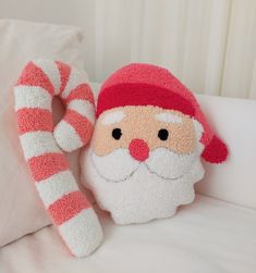 a santa clause stuffed animal sitting on top of a bed next to a candy cane