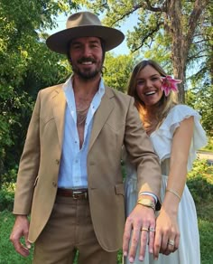 a man and woman are dressed up in wedding attire posing for the camera with their hands on each other's hips