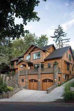 a large wooden house with two garages on the front and second story, surrounded by trees