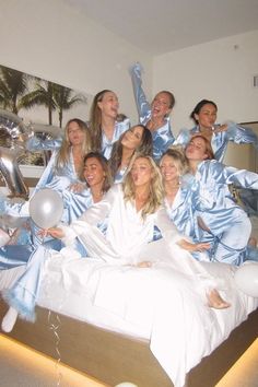 a group of women dressed in blue and white posing for a photo on a bed