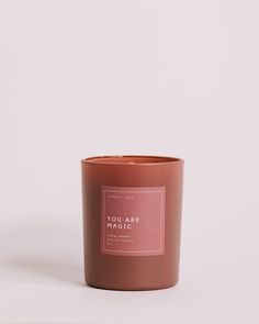 a pink candle with the words you are loved in white lettering on it, against a white background