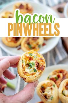 the bacon pinwheels are being held up by someone's hand, with other food in the background