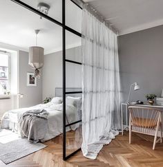 a bedroom with a bed, desk and chair next to a window in the corner