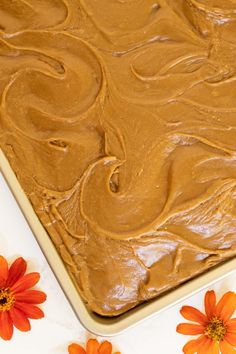 a square cake with frosting and flowers on the side