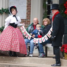 a group of people sitting on top of a bench in front of a christmas tree