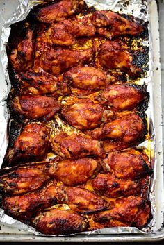 baked chicken wings in tin foil lined up on a baking sheet, ready to be cooked