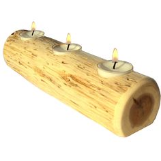 three lit candles are placed on a piece of wood that has been turned into a log