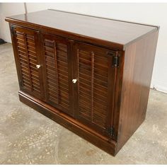 a large wooden cabinet with shutters on the top and bottom, sitting in a room