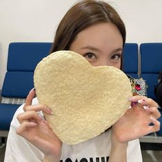 a woman holding up a heart shaped tortilla in front of her face