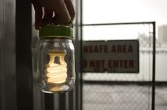 a person holding a mason jar with light bulbs in it and a sign that says safe area don't enter