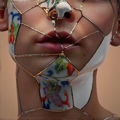 a woman's face is covered in gold wire and has flowers on her neck