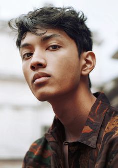 a young man is staring at something while wearing a shirt with an animal print on it