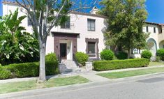 this is an image of a house with bushes and trees on the side walk in front of it