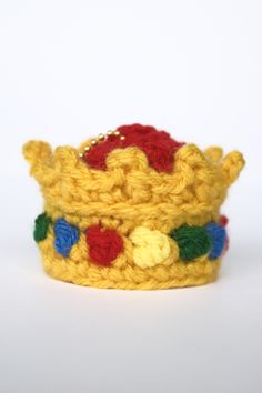 a crocheted yellow crown with red, blue and green flowers on it's sides