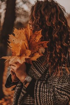 a woman with curly hair holding up a leaf