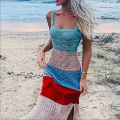 a woman is walking on the beach wearing a colorful dress and sandals with her hand in her pocket