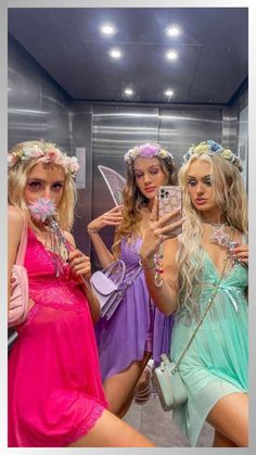 three beautiful women dressed in fairy costumes taking selfies with their cell phones while standing next to each other