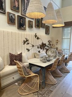 a dining room table with chairs and pictures on the wall above it, along with hanging lights