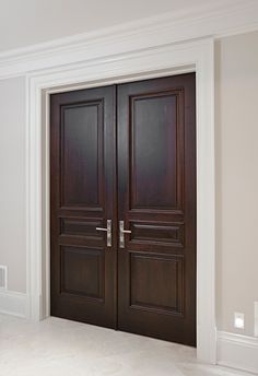 two wooden doors in an empty room with white walls