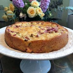 a cake sitting on top of a white plate next to a vase filled with flowers