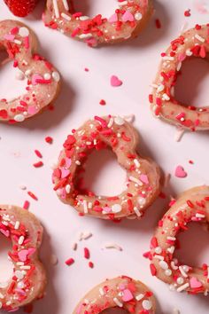 doughnuts with sprinkles and strawberries are arranged on a white surface