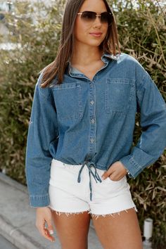 Introducing the DENIM DREAMER CROP TOP, a must-have for any fashion-forward individual. Crafted from high-quality chambray fabric, this crop top features a stylish button front and a versatile drawstring hem. Elevate your wardrobe and achieve a chic look with this trendy piece. Summer Chambray Collared Denim Top, Denim Blue Button-up Top For Day Out, Spring Light Wash Collared Denim Top, Button-up Denim Blue Top For Day Out, Chambray Tops With Pockets For Day Out, Trendy Collared Denim Blue Top, Trendy Collared Denim Top For Day Out, Medium Wash Button-up Tops For Day Out, Medium Wash Denim Jacket For Summer Day Out