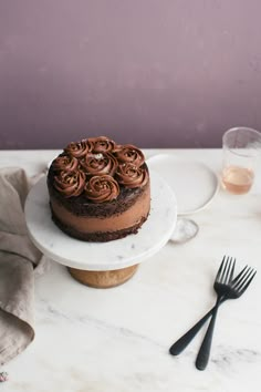 a chocolate cake sitting on top of a white plate next to a fork and knife