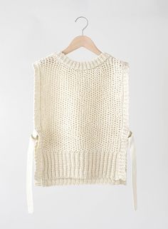 a white sweater hanging on a wooden hanger with a knot at the bottom and an unbuttoned top