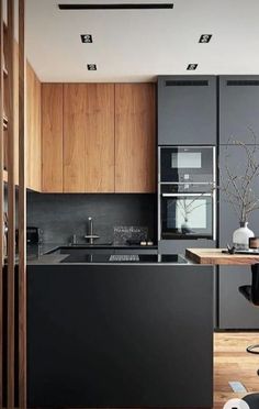 a modern kitchen with wooden cabinets and black appliances, along with a bar stool that matches the hardwood flooring