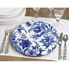 a blue and white plate sitting on top of a wooden table next to silverware