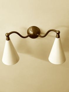 two white lamps hanging from the side of a wall mounted light fixture on a beige wall