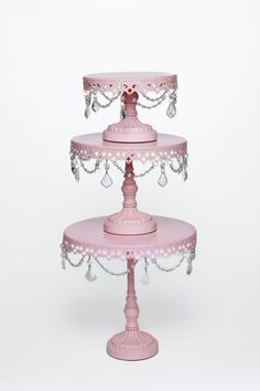 three tiered cake stand with pink polka dots and pearls on the bottom, holding two cakes