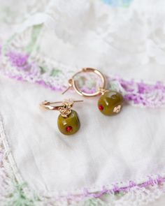 Introducing our Olive earrings! Featuring our brand new Olive charm! <3  Every picnic blanket piece is lovingly designed and handcrafted completely in-house and perfectly finished in our jewellery studio.  Every individual glass feature charm takes around half an hour to delicately form by hand in the flame, reaching temperatures of up to 800 degrees celsius, before heading to the kiln to soak for around 8 hours in the warmth to ensure strength and longevity. The charms are then washed by hand t Whimsical Gold Hoop Earrings For Gift, Whimsical Gold Hoop Earrings As Gift, Whimsical Gold Hoop Earrings Gift, Green Hoop Earrings As A Gift, Handmade Small Hoop Huggie Earrings For Gift, Nickel-free 14k Gold Filled Huggie Earrings As Gift, Handmade Small Hoop Huggie Earrings As Gift, Handmade 14k Gold Filled Drop Huggie Earrings, Handmade 14k Gold Filled Dangle Huggie Earrings