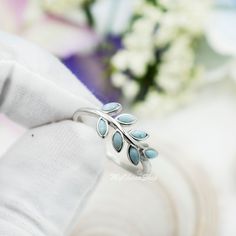 a close up of a person's hand wearing a ring with leaves on it