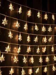 lighted snowflakes are hanging on a string in front of a black background with white lights